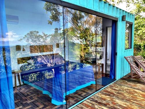 una casa azul con una pared de cristal en una cubierta en Fazenda Vista do Mar, en Serra Grande