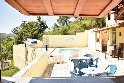 a patio with tables and chairs next to a swimming pool at Pousada Colonetti in Lindóia