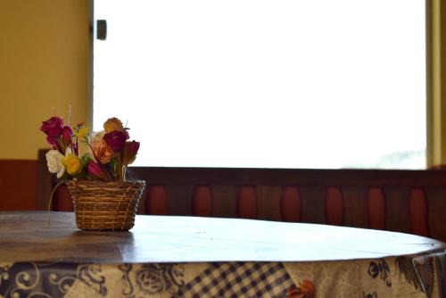 a table with a basket of flowers on it at Pousada Colonetti in Lindóia