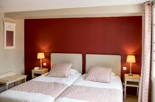 2 letti in una camera da letto con parete rossa di Hôtel du Musée a Arles