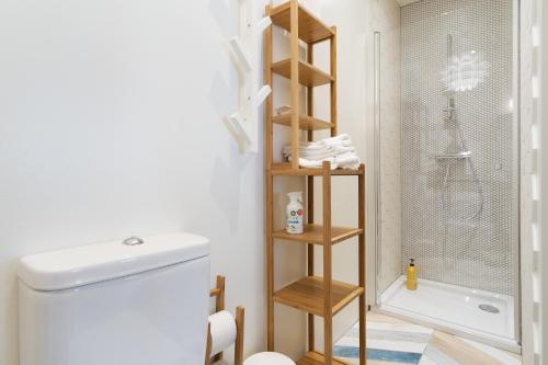 a bathroom with a white toilet and a wooden shelf at Family Apartment in Tallinn