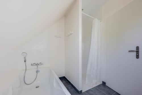 La salle de bains blanche est pourvue d'une douche et d'une baignoire. dans l'établissement TI LAOUEN - 300 m de la plage, à Sarzeau