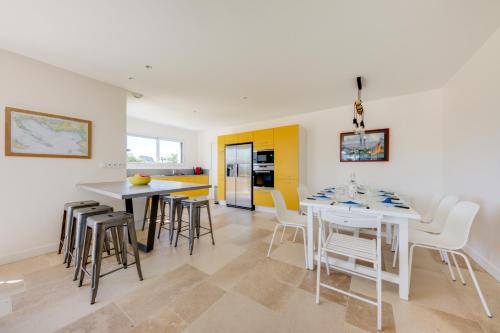 - une cuisine et une salle à manger avec des tables et des chaises blanches dans l'établissement TI LAOUEN - 300 m de la plage, à Sarzeau