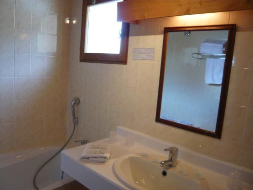 ノートル・ダム・ド・ベルコンブにあるHotel Le Tetrasのバスルーム(シンク、バスタブ、鏡付)