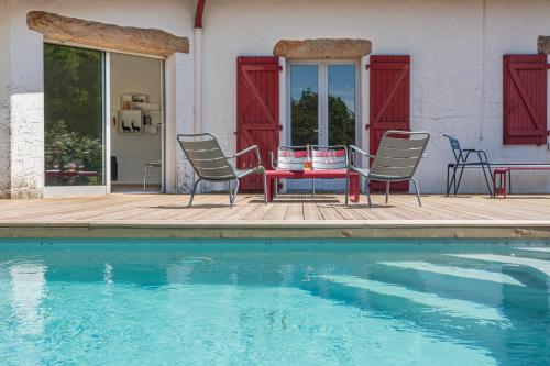 un patio avec une table et des chaises à côté d'une piscine dans l'établissement LANDAGAINA Villa with heated pool and garden Guethary close to Biarritz, à Guéthary