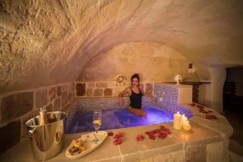 a woman sitting in a bath tub in a cave at La Dimora del Principe in Grottaglie