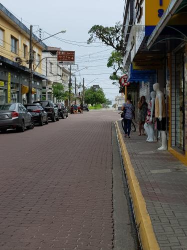a group of people walking down a city street at Suítes Suarão in Itanhaém