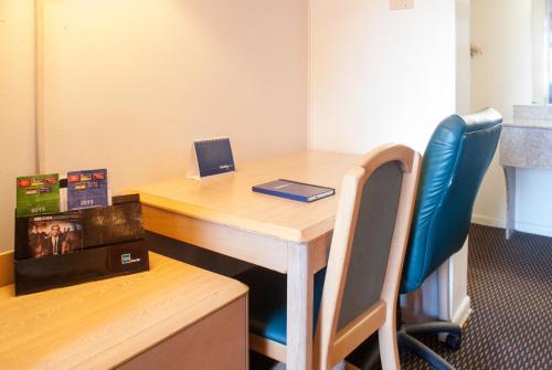 an office with a wooden desk and a blue chair at Scottish Inn Downtown Jacksonville in Jacksonville