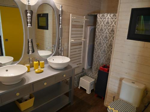 une salle de bain avec deux lavabos et un grand miroir dans l'établissement Le Gage location de vacance à la semaine, à Saint-Brévin-lʼOcéan