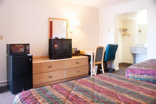 a hotel room with a tv on a dresser and a bed at Scottish Inn Downtown Jacksonville in Jacksonville