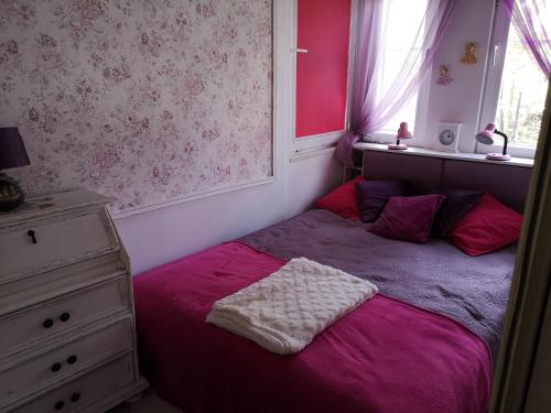 a bedroom with a purple bed with a window and a dresser at Mieszkanie Przy Plaży in Sopot
