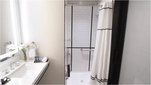 a white bathroom with a shower and a sink at Arlo Chicago in Chicago
