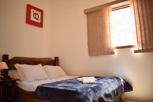 a bedroom with a bed with a blue blanket on it at Pousada Colonetti in Lindóia