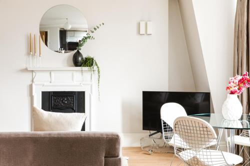 a living room with a fireplace and a table and chairs at 56 Welbeck Street in London