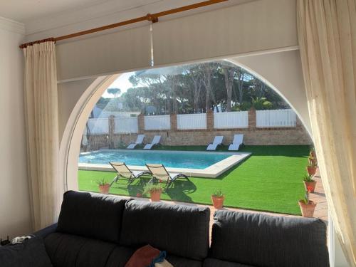 a living room with a couch and a view of a pool at La Quinta - La Barrosa in Chiclana de la Frontera