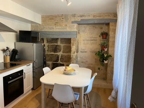 een kleine keuken met een witte tafel en stoelen bij Aventurine in Terrasson