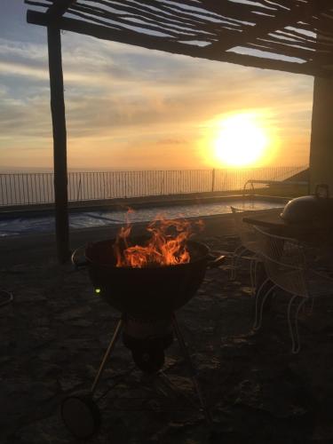 una hoguera en la playa con la puesta de sol en el fondo en Villa Pargo, en Fajã da Ovelha