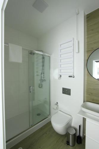uma casa de banho branca com um chuveiro e um WC. em Łazienna Premier em Toruń