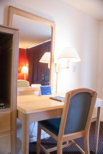 a desk with a mirror and a table with a chair at Scottish Inn Downtown Jacksonville in Jacksonville