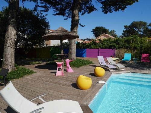 - une piscine avec des chaises, une table et un parasol dans l'établissement Le Gage location de vacance à la semaine, à Saint-Brévin-lʼOcéan