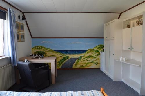 een kamer met een bureau en een schilderij aan de muur bij De strandkamer in Oostkapelle
