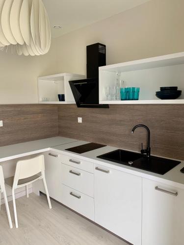 a kitchen with white cabinets and a sink and a table at APARTAMENTY POSEJDON in Świnoujście