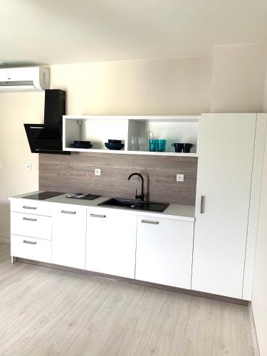 a kitchen with white cabinets and a sink at APARTAMENTY POSEJDON in Świnoujście