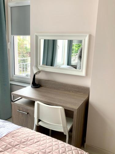 a bedroom with a desk with a mirror and a chair at APARTAMENTY POSEJDON in Świnoujście
