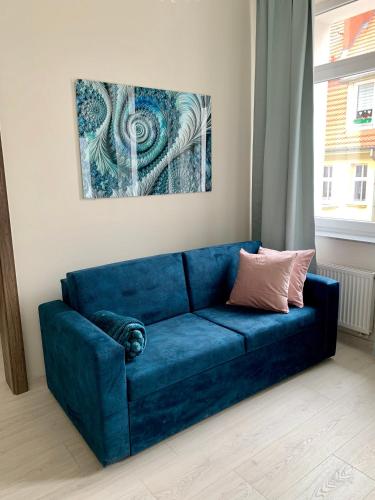 a blue couch in a living room with a painting at APARTAMENTY POSEJDON in Świnoujście