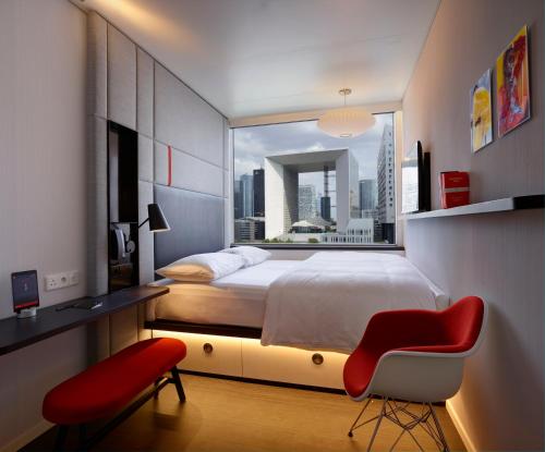 una camera con un grande letto e una sedia rossa di citizenM Paris La Défense a Nanterre