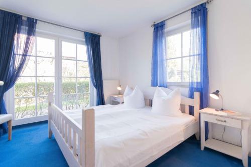 - une chambre dotée d'un lit blanc, de parquet bleu et de fenêtres dans l'établissement Strandoase Typ STO-A STRANDOASE Whg. SO6, à Wustrow