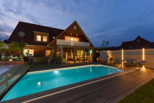 a house with a swimming pool and a wooden deck at Ferienwohnung Haus zum Seehund mit Pool und Frühstücksoption in Bensersiel