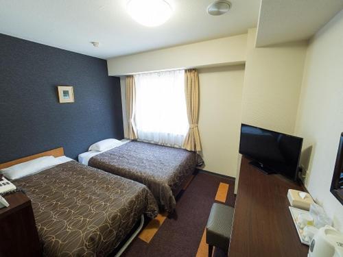 Habitación de hotel con 2 camas y TV de pantalla plana. en Hotel Shin Osaka / Vacation STAY 81525 en Osaka