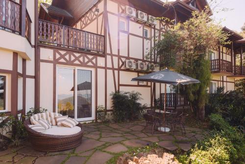 a house with a patio with an umbrella and a table at Hotel Jardins da Colina in Nova Petrópolis
