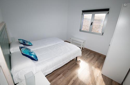 a white bedroom with a bed and a window at Casa Playa Ondina in Gáldar