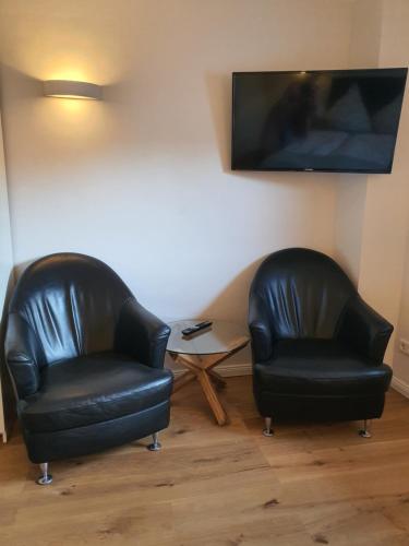 two black leather chairs and a table in a room at Nordsee-Pension Dagebüll in Dagebüll