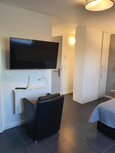 a room with a flat screen tv and a chair at Nordsee-Pension Dagebüll in Dagebüll