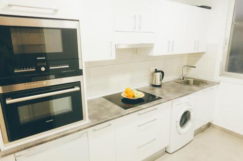 eine weiße Küche mit einer Spüle und einer Mikrowelle in der Unterkunft GROS ZURRIOLA BEACH WIFI TERRACE PARKING 20E night in San Sebastián