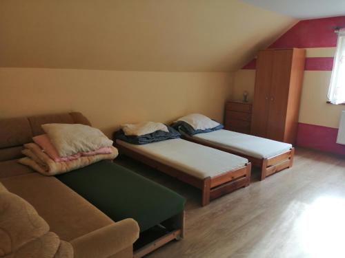 een kleine kamer met 2 bedden en een bank bij W zieleni in Polanica-Zdrój