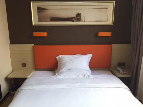 7Days Premium Lianyungang Guanyun Nanjing West Road Hesheng Square Branch في Guanyun: غرفة نوم مع سرير مع لوح برتقالي للرأس