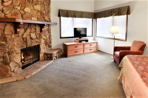 a living room with a stone fireplace and a television at Snow Lake Lodge in Big Bear Lake