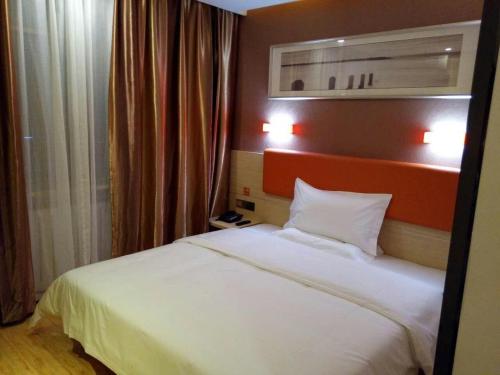 a bedroom with a white bed with two pillows at 7 Days Premium Hami City Government Branch in Qumul