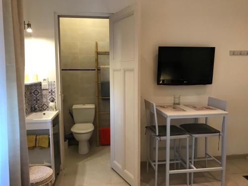a bathroom with a toilet and a tv on the wall at Le Marty in Narbonne
