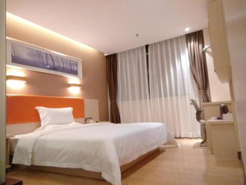 a bedroom with a large white bed and a window at 7Days Premium Meizhou Fengshun Store in Tangkeng
