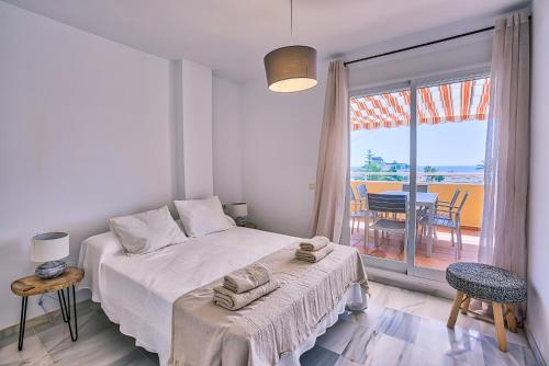 a white bedroom with a bed and a balcony at Sur Suites Torremolinos in Torremolinos