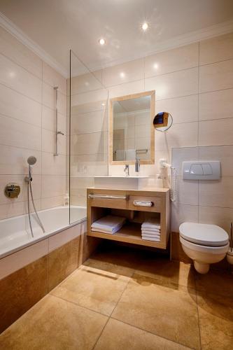 a bathroom with a sink and a toilet and a tub at Der Postwirt in Söll
