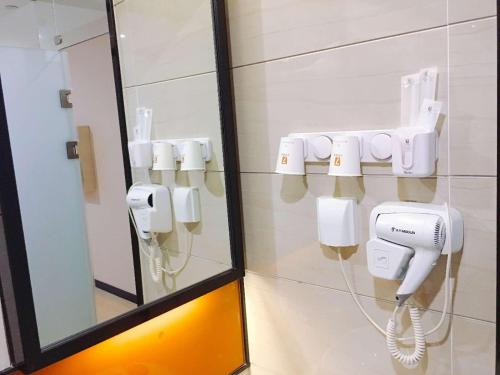 une salle de bains avec une rangée de téléphones sur le mur dans l'établissement 7Days Premium Shijiazhuang Luquan Shangzhuang Branch, à Shijiazhuang