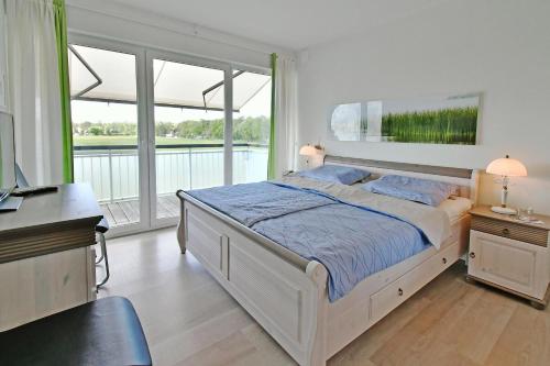 - une chambre avec un grand lit et un balcon dans l'établissement FeWo SEEWIESE, à Dierhagen