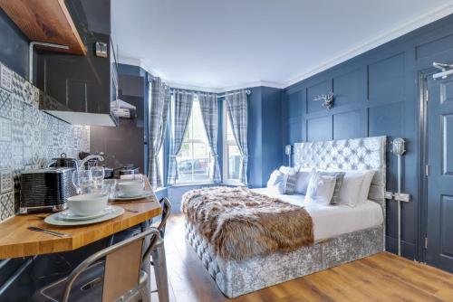 a bedroom with blue walls and a bed and a kitchen at SixtySix by Sorted Stay in Southend-on-Sea