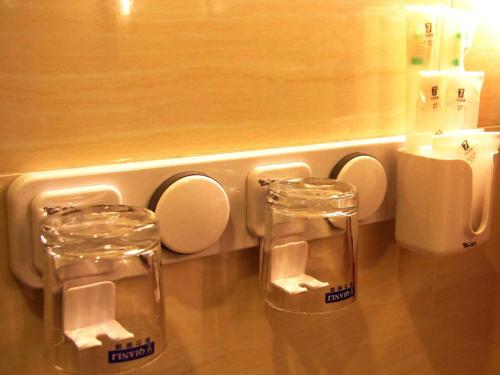 two glass jars sitting on a counter next to a urinal at 7Days Premium Leshan Qianwei Fengye Fortune Center Branch in Leshan